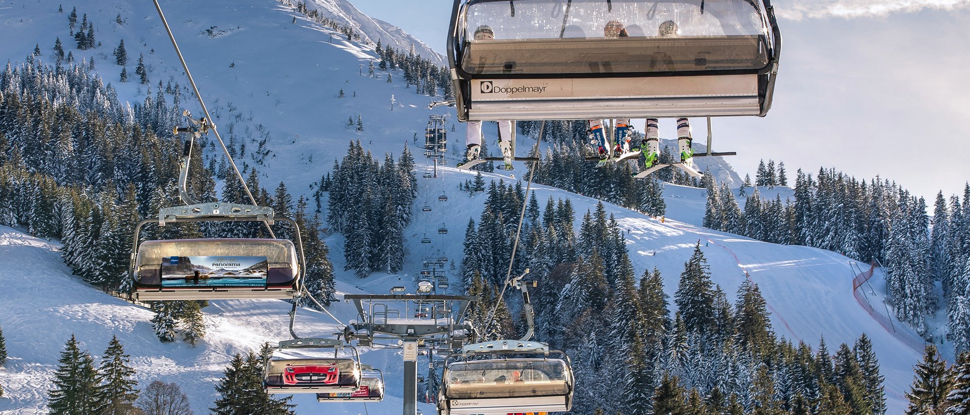 Skifahren lernen im Herzen des Allgäus Skilift mit Skifahrern vor verschneiten Bergen und Tannenbäumen