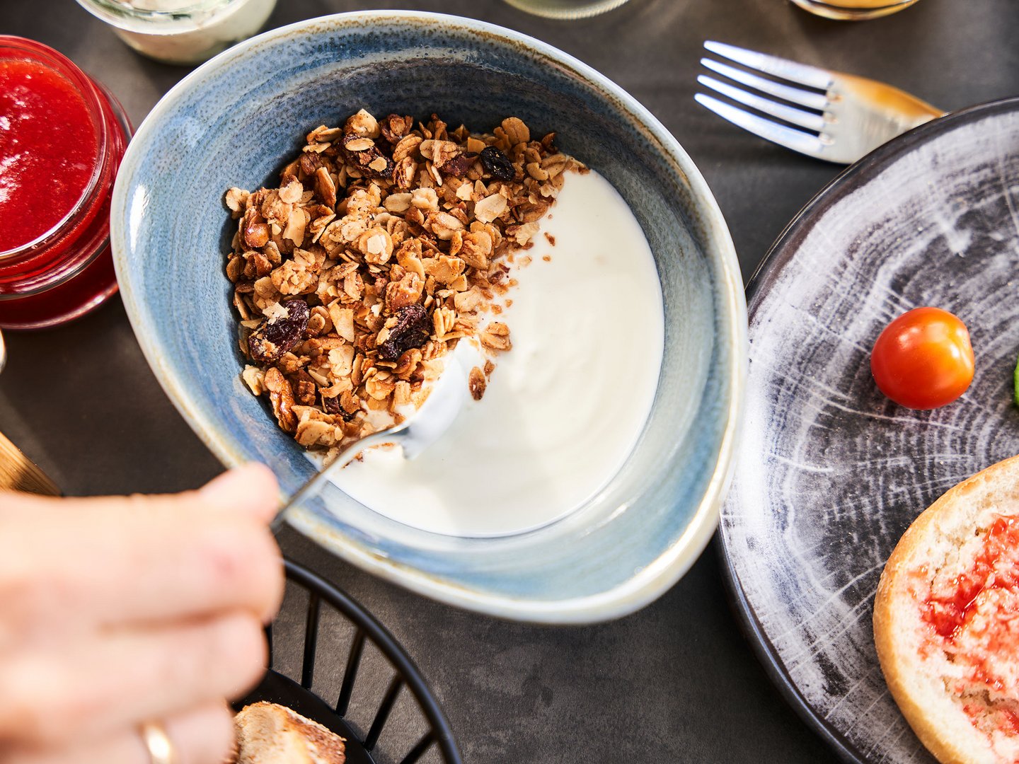 Alpin Lodges: zubuchbare Extras Schüssel mit Joghurt und Granola, dazu Marmelade, Gemüse und Brot auf dem Tisch